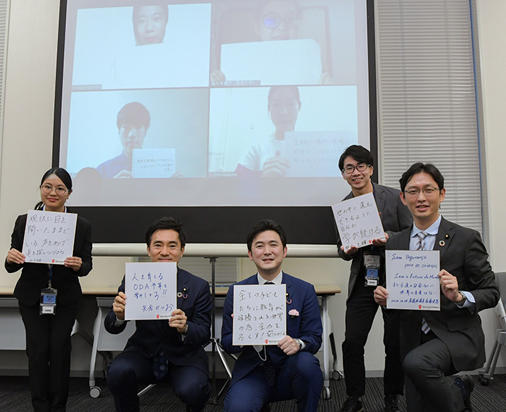国際貢献への決意をつづった色紙を手に大学生と語り合う矢倉委員長（左から2人目）ら＝14日　参院議員会館