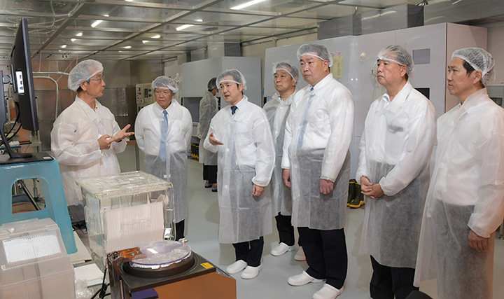 熊本大を訪れ、半導体研究について説明を聞く安江政務官（左から3人目）ら＝16日　熊本市